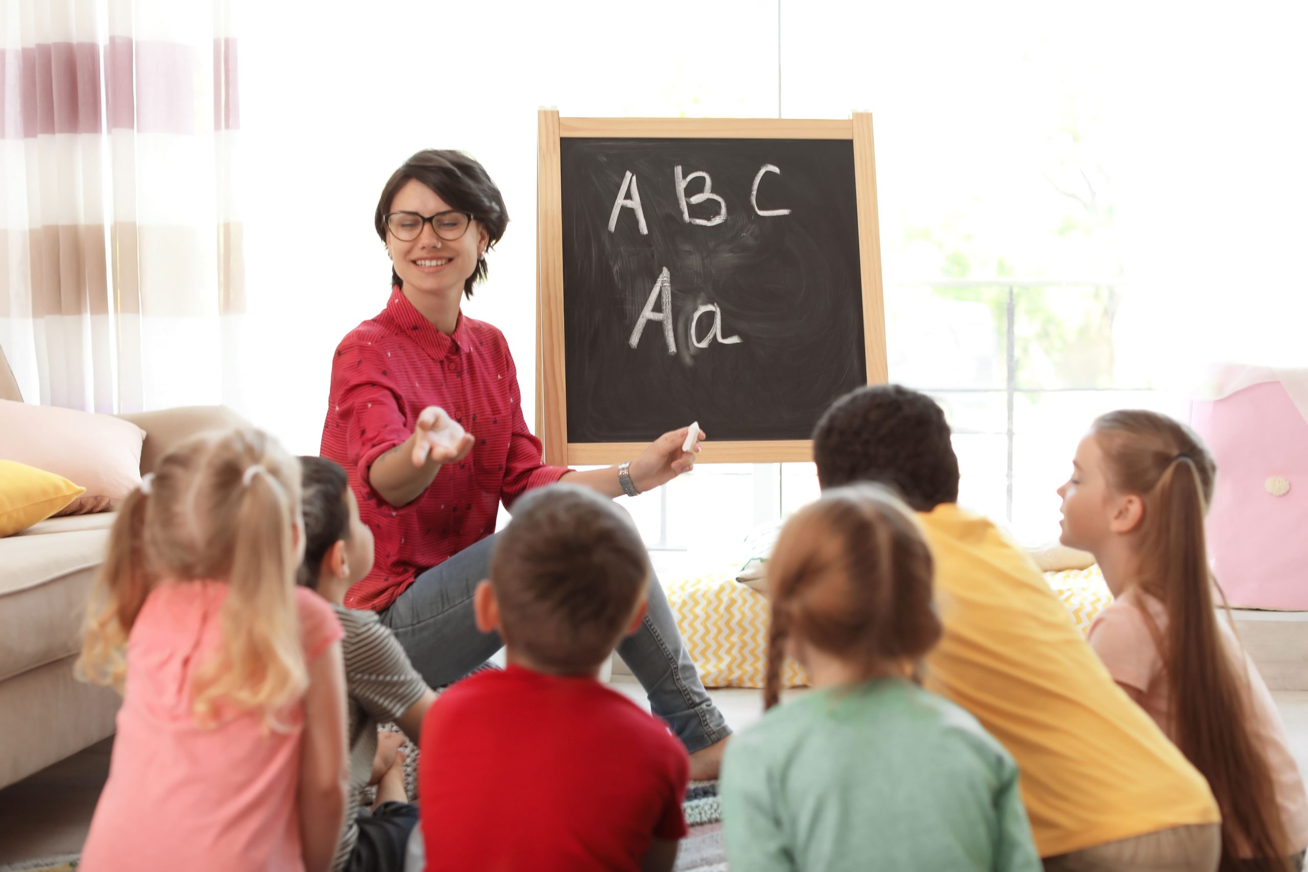 Profesora enseñando inglés a niños pequeños en una clase interactiva
